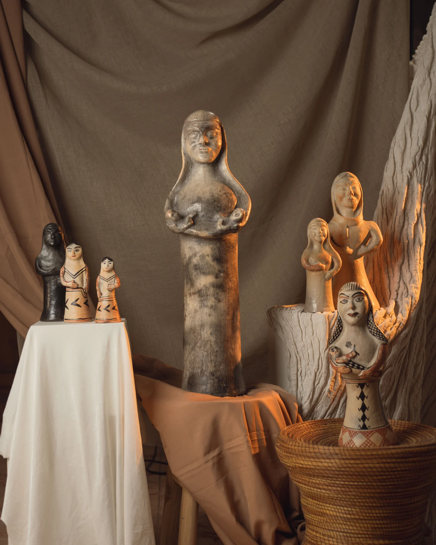 Statuettes en poterie de Sejnane réunies dans un atelier, sur drapés et paniers