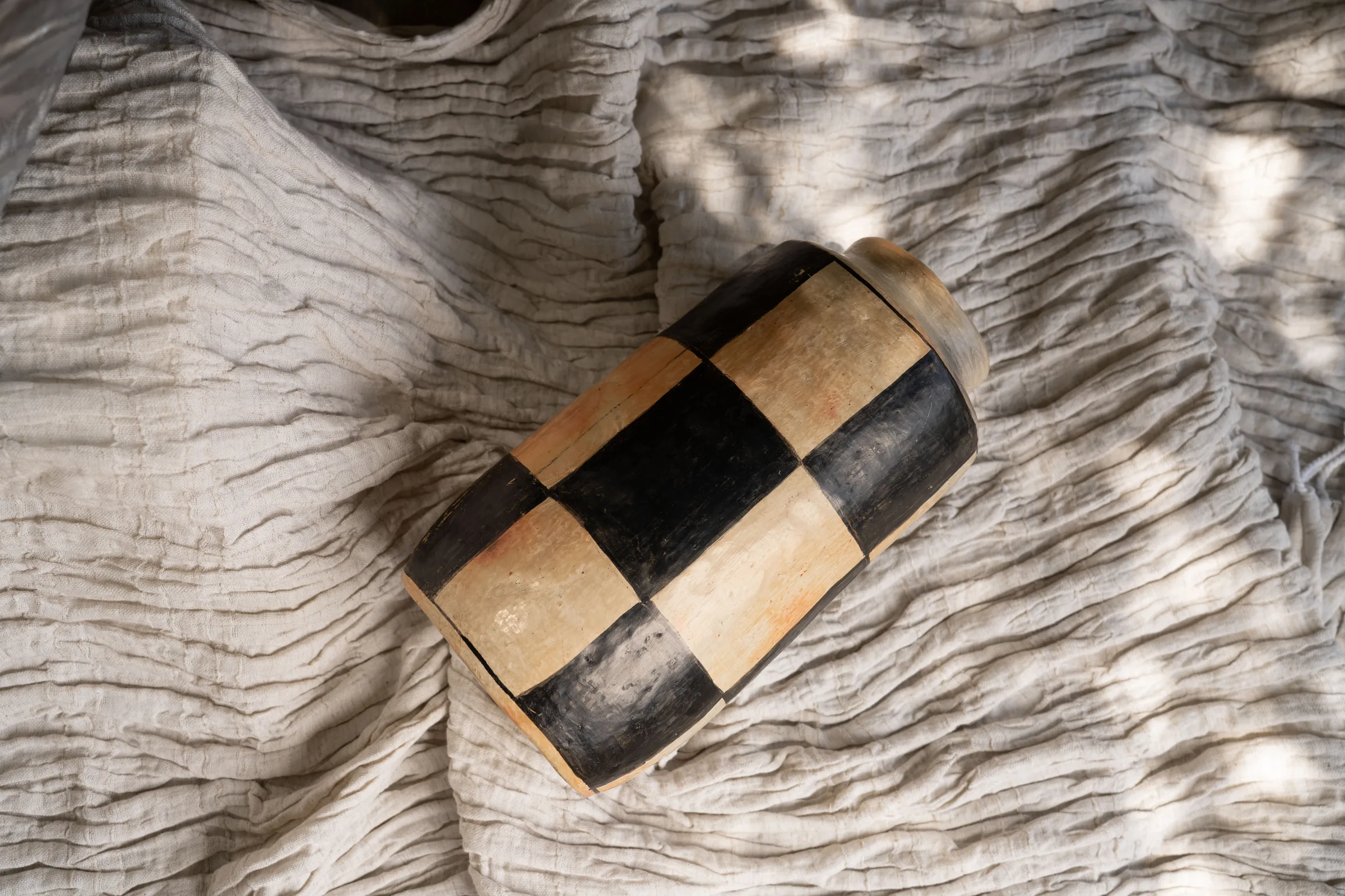 Vase en poterie de Sejnane à motif damier posé sur un drapé de lin, séries professionnelles