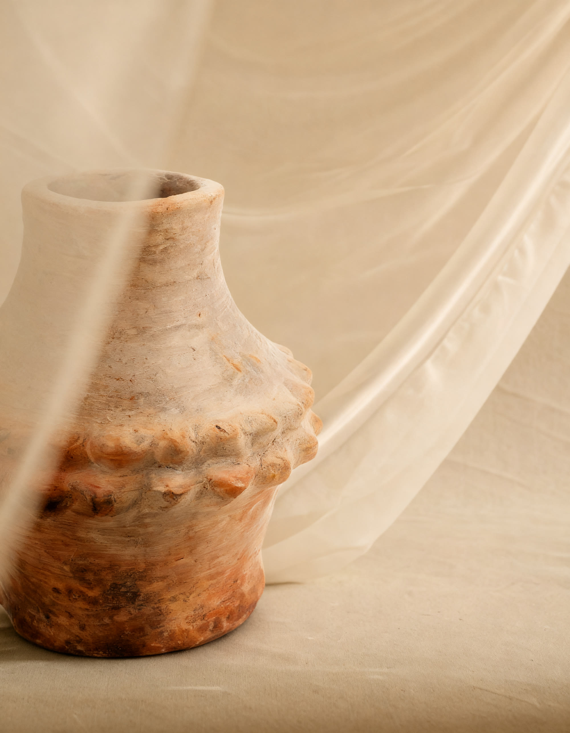Vase en poterie de Sejnane aux anses perlées posé sur un drapé de lin